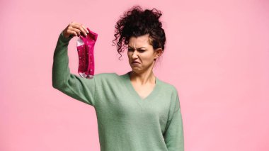  grimacing woman holding stinky socks isolated on pink clipart