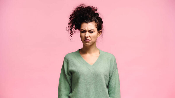 young woman grimacing while feeling disgusted isolated on pink