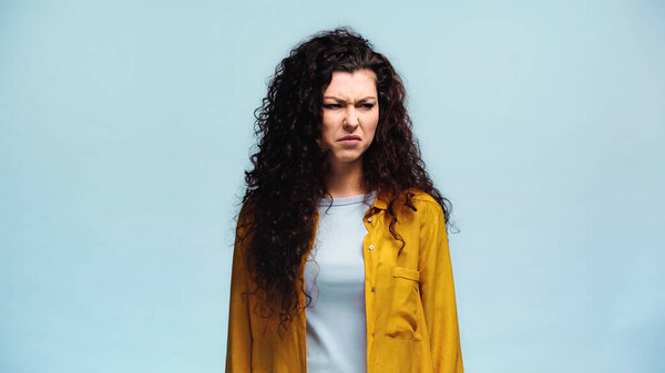 disgusted woman frowning while looking away isolated on blue