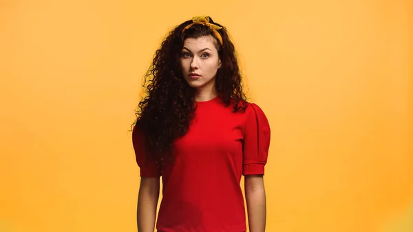 Stock image discouraged woman with wavy hair looking at camera isolated on orange