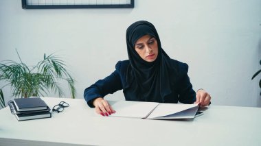 Muslim businesswoman working with papers in office  clipart