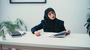 Başörtülü Müslüman iş kadını ofiste kağıtlarla çalışıyor 