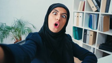 young muslim businesswoman grimacing while taking selfie  clipart