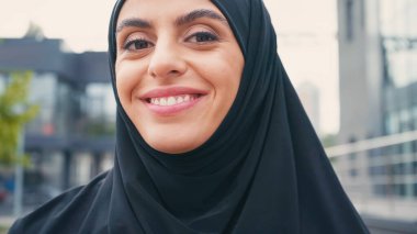 close up of joyful muslim woman in hijab woman looking at camera outside  clipart