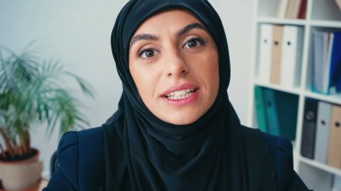 Başörtülü genç Müslüman iş kadını kameraya bakarken konuşuyor