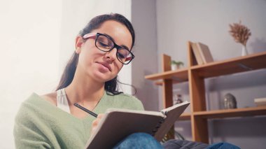 Genç öğrenci evde bulanık not defterine yazıyor. 