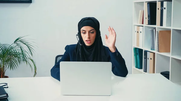 Mujer Musulmana Gesto Auriculares Mientras Usa Ordenador Portátil Centro Llamadas — Foto de Stock