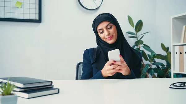 Mujer Negocios Musulmana Sonriente Usando Teléfono Inteligente Cerca Portátiles Mesa — Foto de Stock