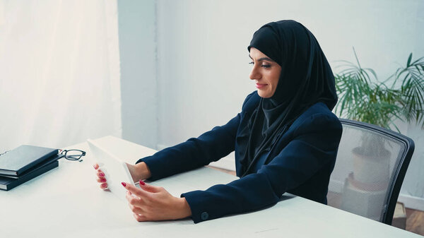 pleased muslim businesswoman using digital tablet in office 