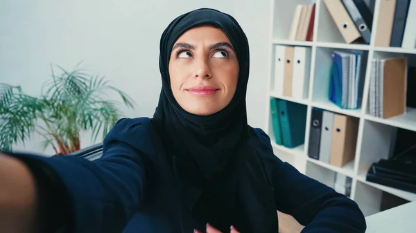 Smiling Young Muslim Businesswoman Looking Away While Taking Selfie — Stock Photo, Image
