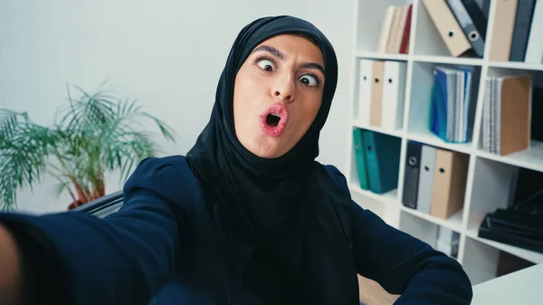 stock image young muslim businesswoman grimacing while taking selfie 