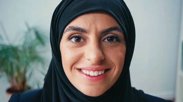 close up of joyful muslim businesswoman looking at camera in office