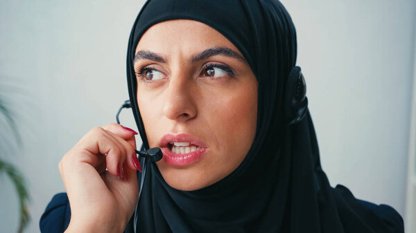 woman in hijab using microphone while talking in office 