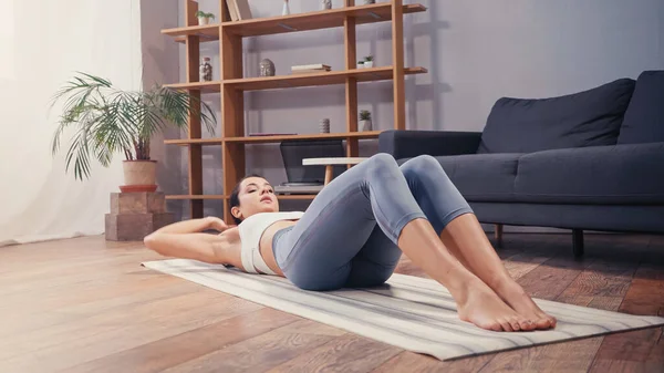 女运动员在家里训练时躺在健身垫上 — 图库照片