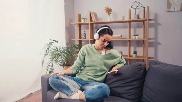 Smiling Woman Wireless Headphones Using Smartphone Couch — Stock Photo, Image