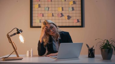 Dizüstü bilgisayarın yanında oturan yorgun iş kadını ve ofiste haplar 