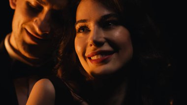 Bulanık erkek arkadaşının yanında gülümseyen neşeli genç bir kadın. 