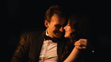 Takım elbiseli, gülümseyen adam siyahların izole edilmiş neşeli kız arkadaşına sarılıp flört ediyor. 