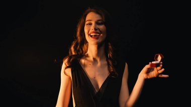 Kırmızı kutulu elbisesi olan, siyah yüzüklü, hayrete düşmüş genç bir kadın. 