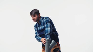 Üniformalı tesisatçı plastik boruyu beyazın üzerinde tutuyor.