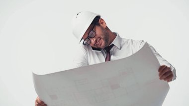 Gülümseyen mühendis akıllı telefondan konuşuyor ve bulanık planı beyaz üzerinde tutuyor.
