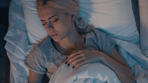 Вид сверху на блондинку, спящую на кровати по ночам 