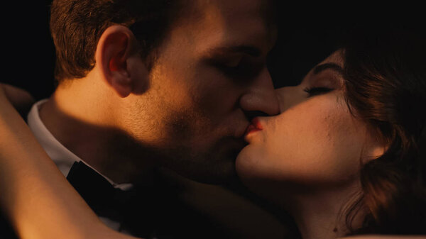 close up of young couple kissing isolated on black 