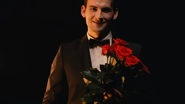 Ευτυχισμένος Νεαρός Άνδρας Κρατώντας Κόκκινα Τριαντάφυλλα Και Χαμογελώντας Απομονωμένος Στο — Φωτογραφία Αρχείου