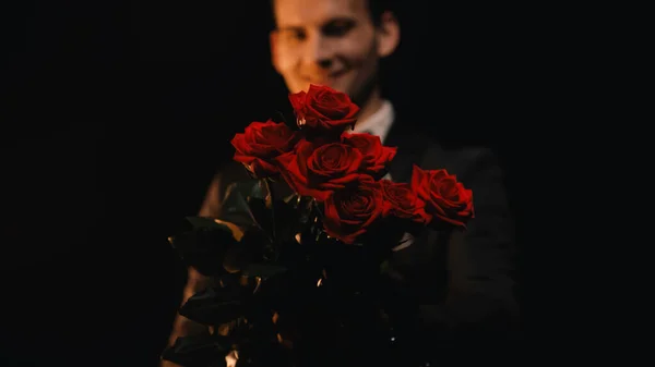 Uomo Felice Sfocato Che Tiene Rose Rosse Isolate Sul Nero — Foto Stock