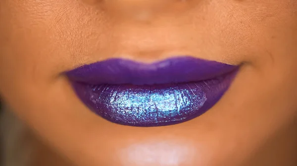 cropped view of woman with shiny lip gloss on purple lips