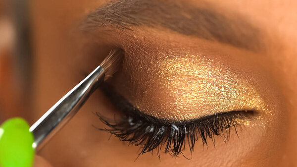 cropped view of african american woman applying eye shadow with cosmetic brush 