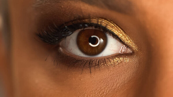 partial view of african american woman with brown eye and golden eye shadow