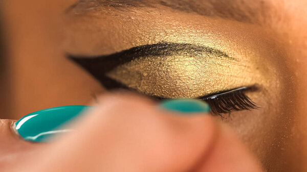 cropped view of african american woman apply black false eyelashes 
