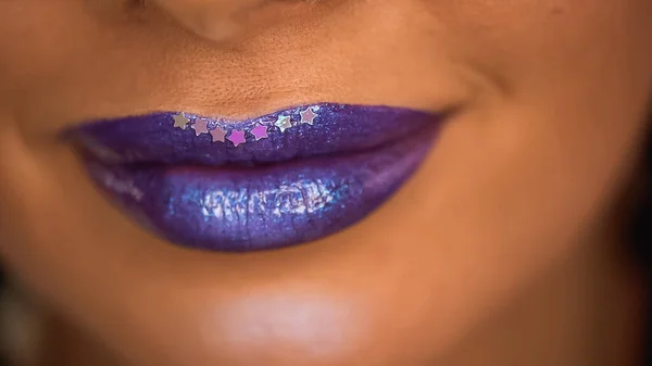 cropped view of smiling woman with stars on purple lips with shimmer