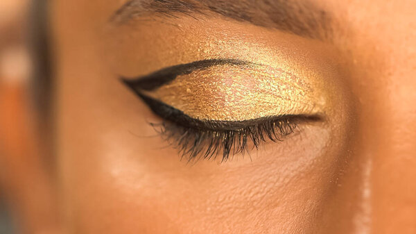 cropped view of african american woman with black eye liner and golden eye shadow