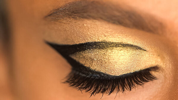 cropped view of african american woman with eye liner and golden eye shadow
