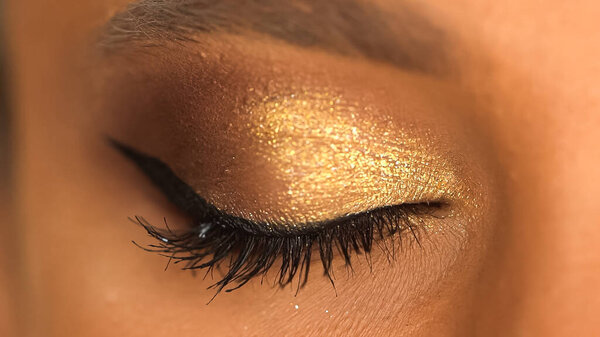 cropped view of african american woman with closed eye and golden eye shadow