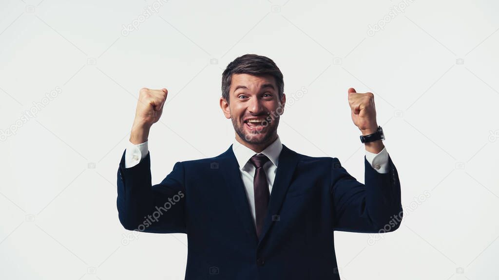 Excited businessman in suit looking at camera while showing yes gesture isolated on white