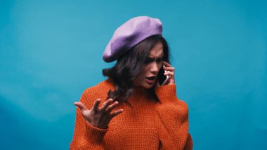 Endişeli bir kadın cep telefonuyla konuşurken mavi ile konuşuyor.