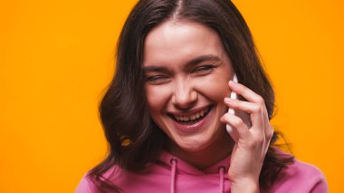 heyecanlı esmer kadın cep telefonuyla gülerken sarıda izole edilmiş.