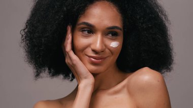 Yüzünde kozmetik kremi olan mutlu bir Afrikalı Amerikalı kadın.