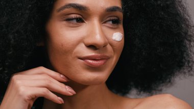 Yüzünde kozmetik kremi olan mutlu Afro-Amerikan kadın.