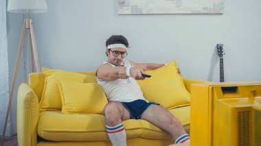 Spor giyim sektöründe tembel bir adam oturma odasındaki kanepede otururken kanal değiştiriyor.