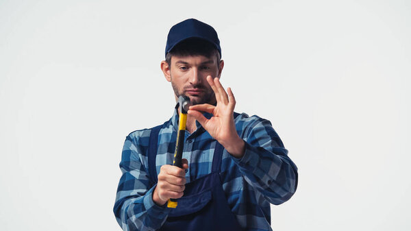 Разнорабочий в комбинезоне держит Хаммер изолированным на белом