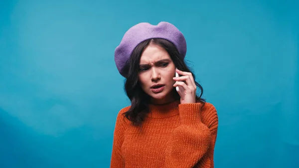 Mulher Tensa Boina Roxa Falando Telefone Celular Isolado Azul — Fotografia de Stock