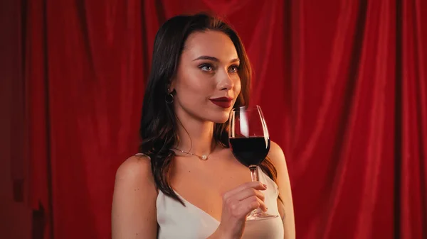 Genç Bir Kadın Elinde Şarap Kadehi Kırmızıda Gülümsüyor — Stok fotoğraf
