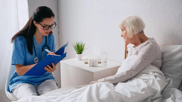 Brunette Nurse Eyeglasses Writing Prescription Clipboard Senior Woman — Stock Photo, Image