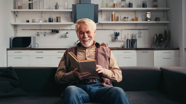 Sonriendo Hombre Mayor Leyendo Libro Casa — Foto de Stock