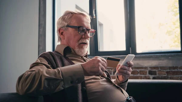 Pensioner Eyeglasses Using Smartphone Holding Credit Card Home — Stock Photo, Image