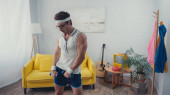 Sportovec v brýlích a sportovní oblečení zvedání činky v retro obývacím pokoji